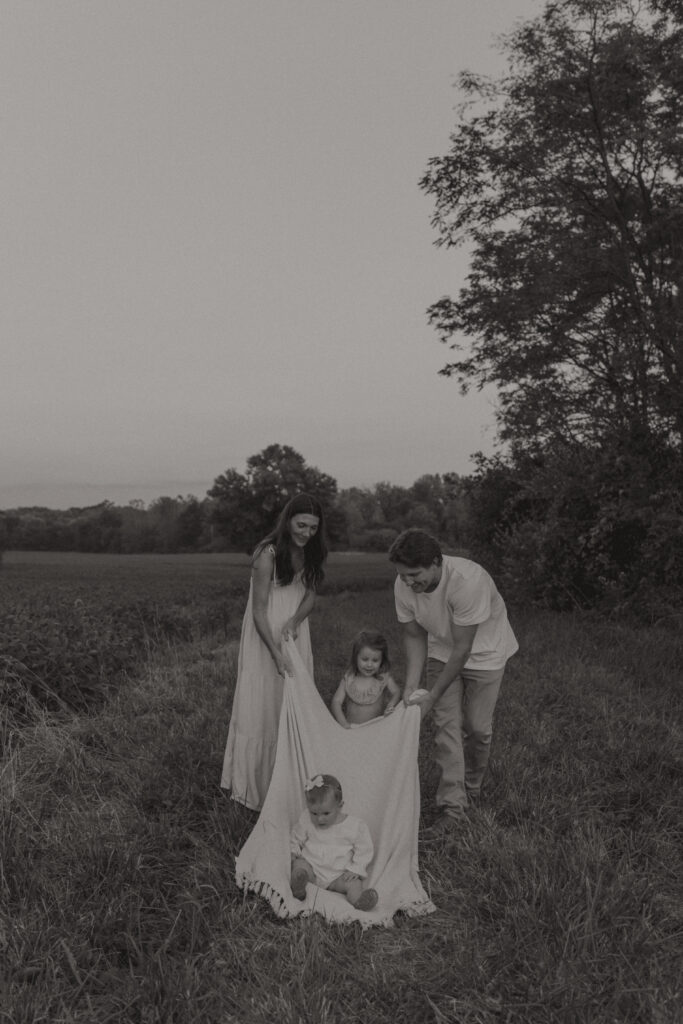 Lifestyle family photography session with playful children in a grassy field in Indiana 
